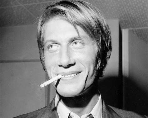 Portrait noir et blanc de Jacques Dutronc, sourire en coin et cigarette aux lèvres.